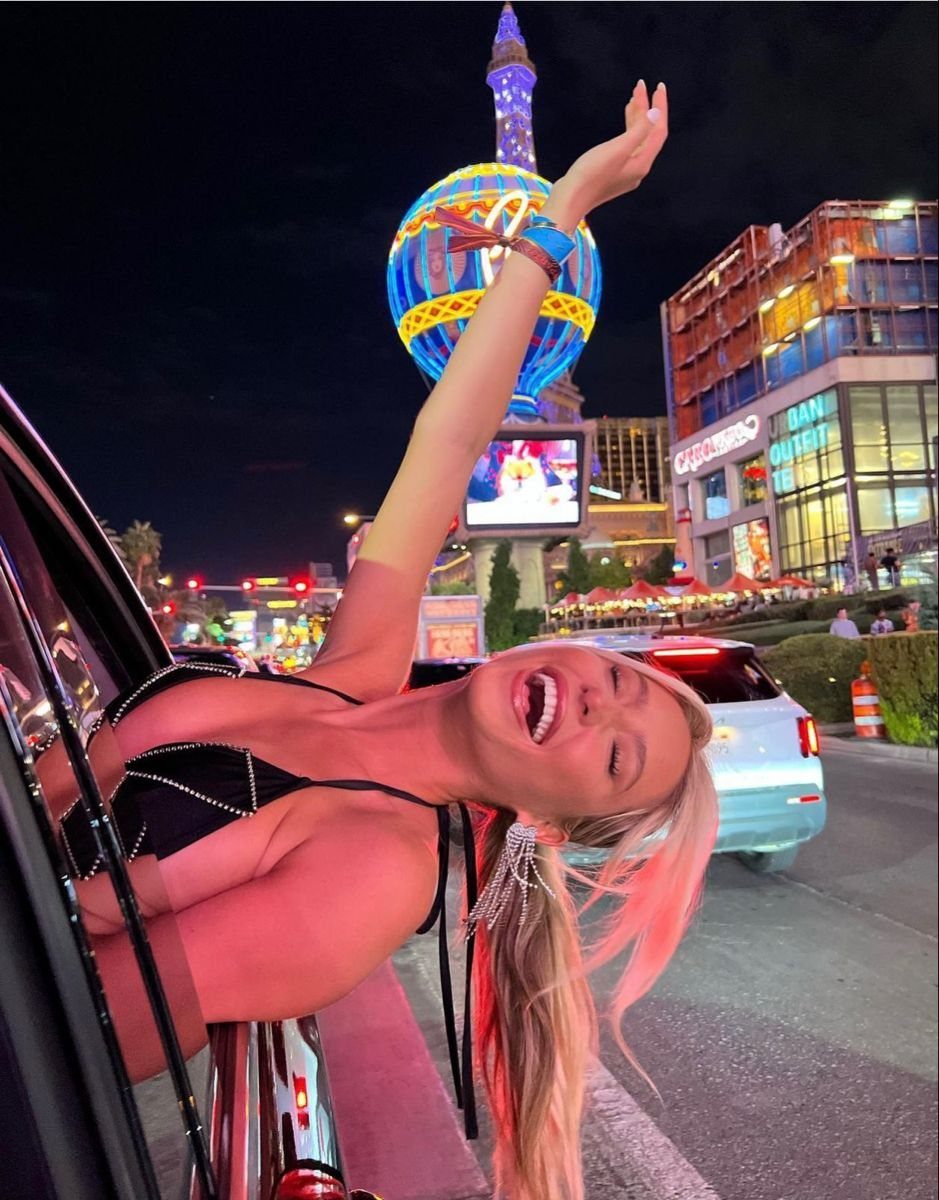 Joyful young woman leaning out of a car on the Las Vegas Strip at night