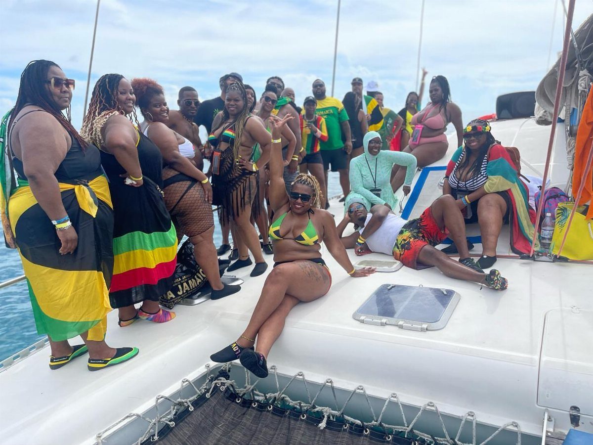 Group of people in colorful attire posing on a white catamaran boat deck.