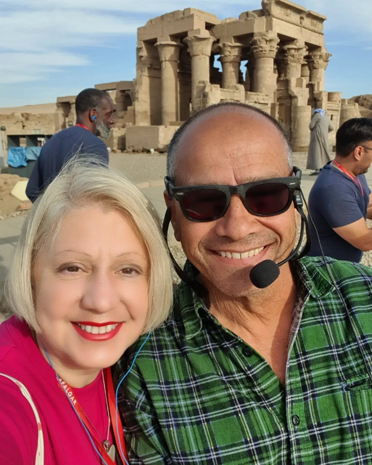 Smiling couple posing in front of an ancient Egyptian stone temple with columns.