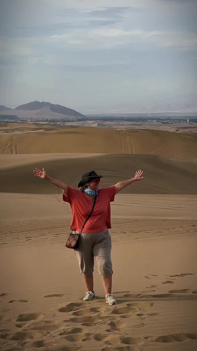 Woman with arms wide open standing on a large desert sand dune