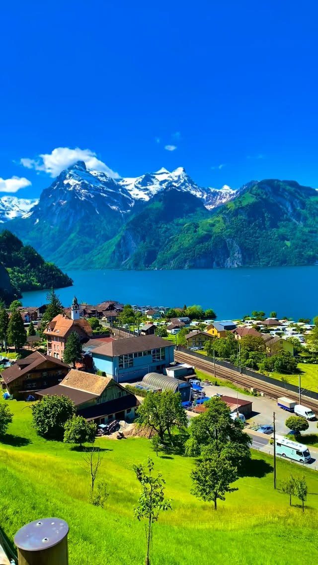 Scenic village by a blue lake with snow-capped mountains under a clear sky