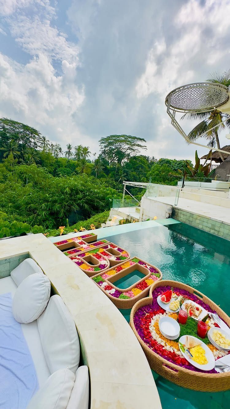 Floating breakfast trays with flowers in a luxury infinity pool overlooking a tropical jungle.