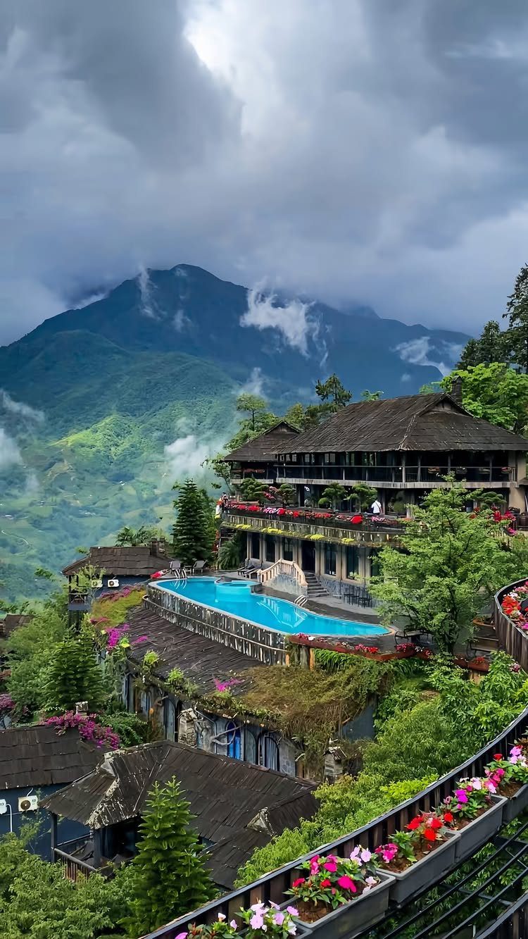 Luxury hillside resort with a blue swimming pool overlooking misty green mountains