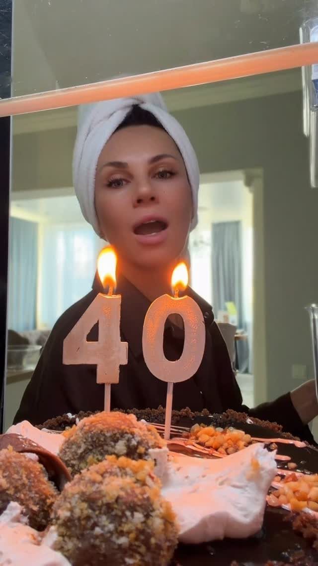 Woman in a robe and head towel celebrating her 40th birthday with cake.