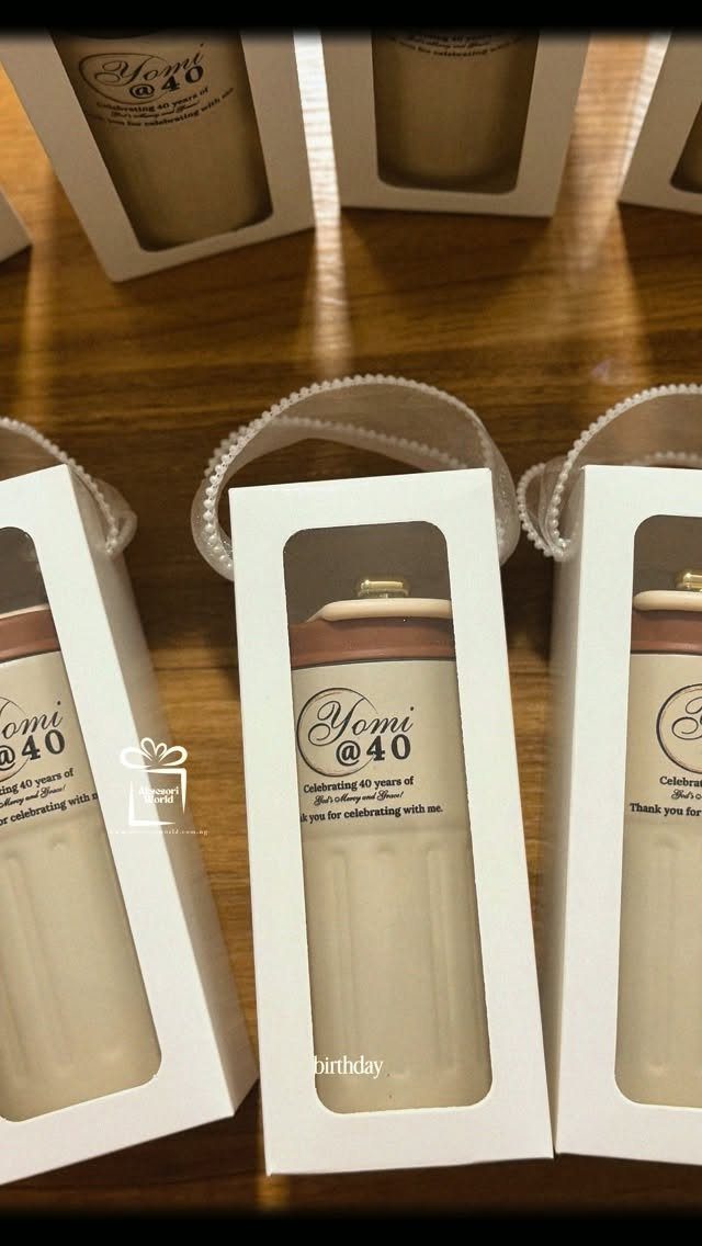 White gift boxes containing tan cylindrical favors with Yomi @ 40 labels.