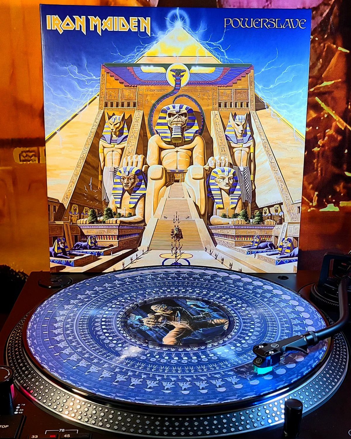 Blue vinyl record on a turntable with Iron Maiden album cover in background