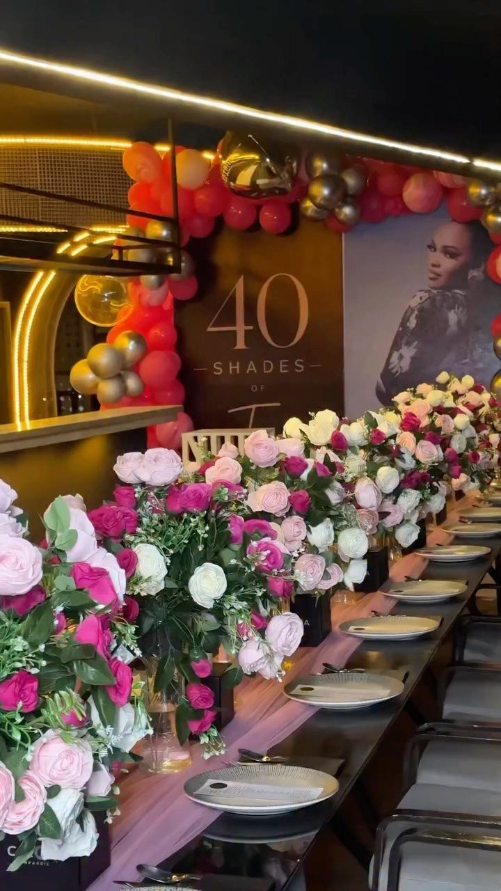 Decorated birthday table with pink roses, balloons, and a 40th birthday sign.