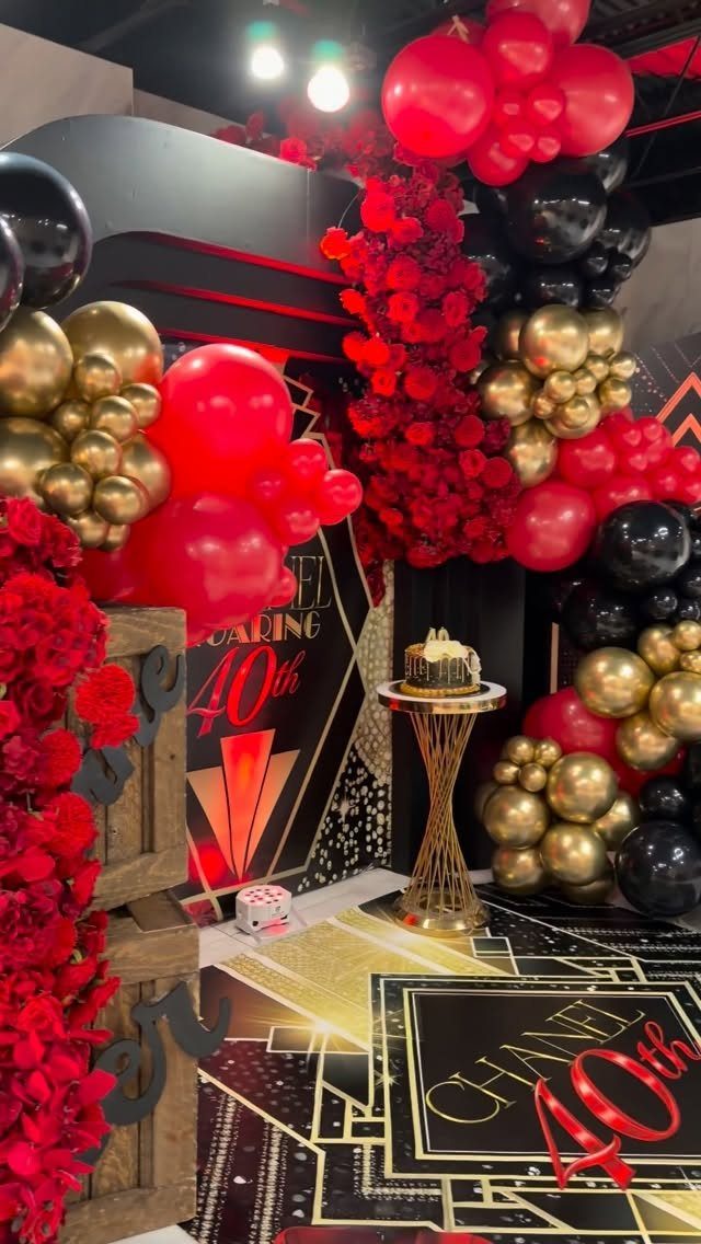 Lavish 40th birthday party decoration with red, gold, and black balloons and flowers.