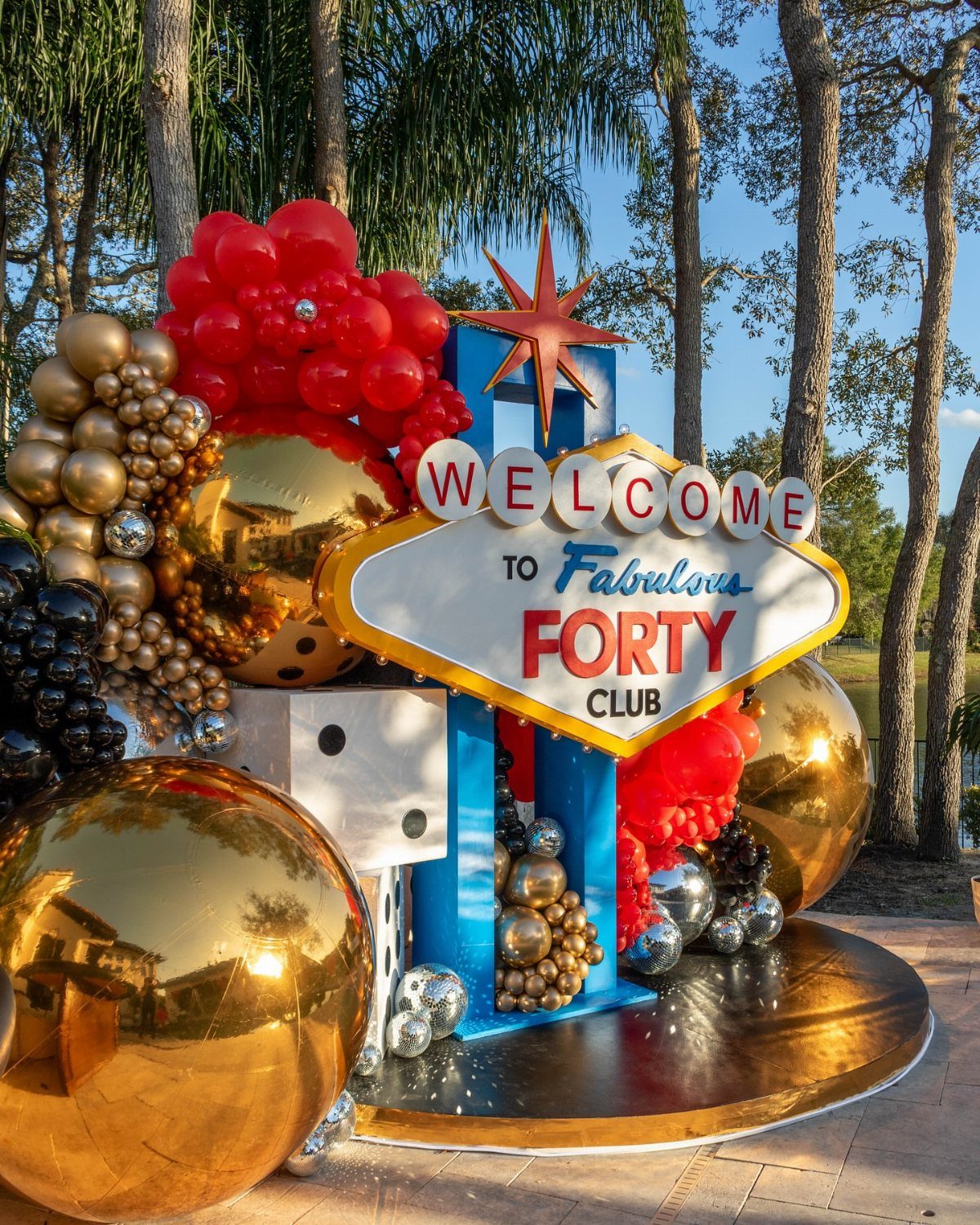 Elaborate 40th birthday party decoration with red and gold balloons and a welcome sign.