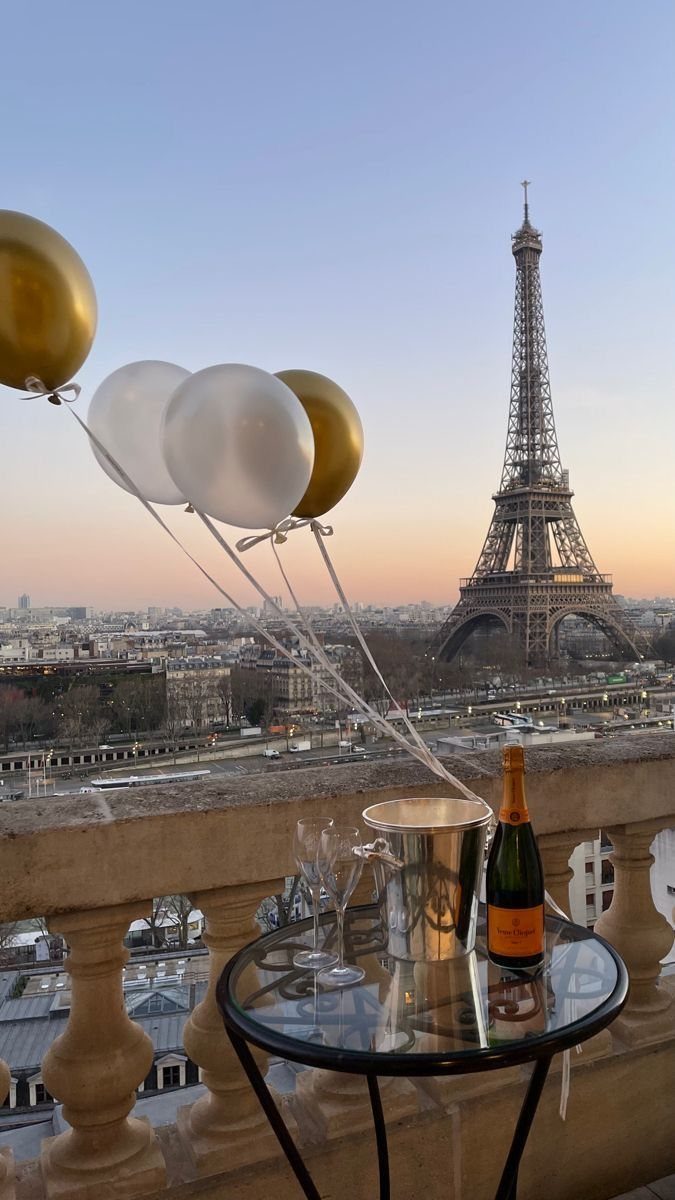 Champagne and balloons on a balcony overlooking the Eiffel Tower at sunset
