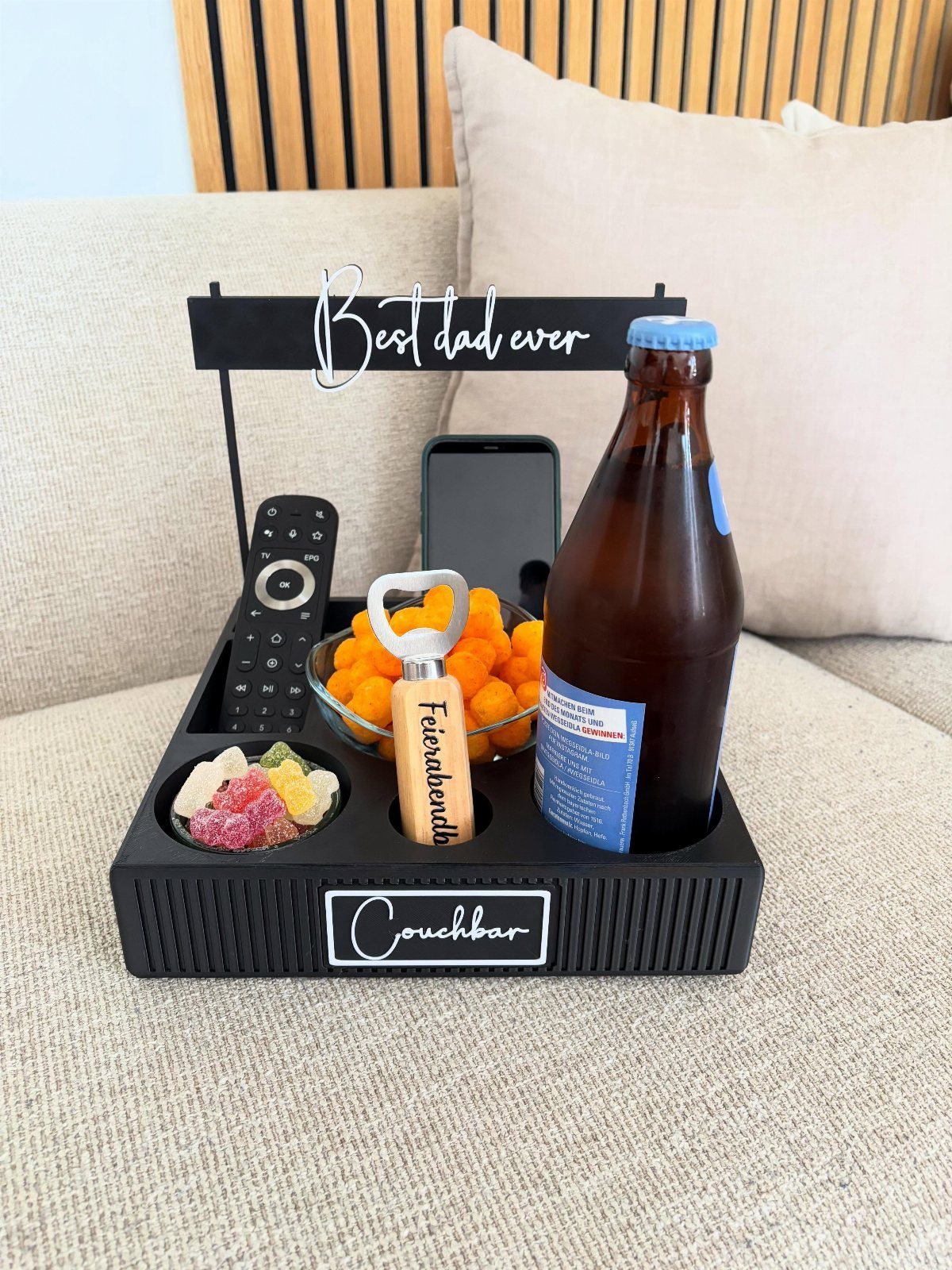 Black couch caddy with beer, snacks, and a Best dad ever sign.