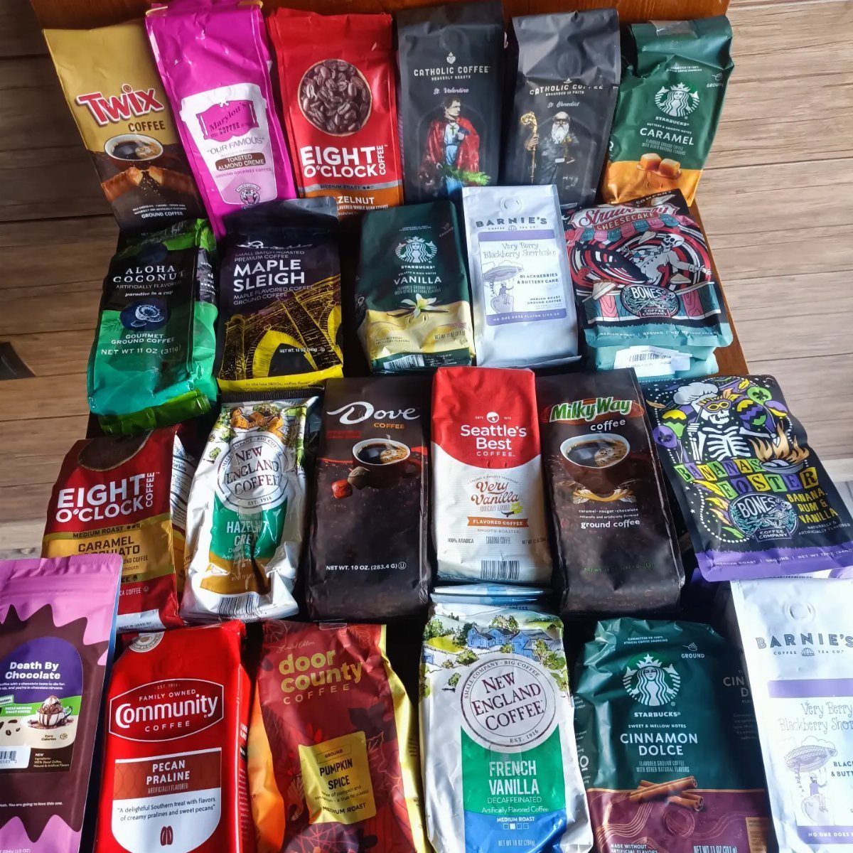 Various branded coffee bags arranged on a wooden surface in a large collection.