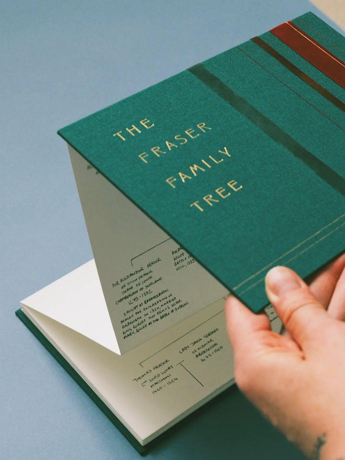Green hardcover book titled The Fraser Family Tree showing handwritten genealogical diagrams.