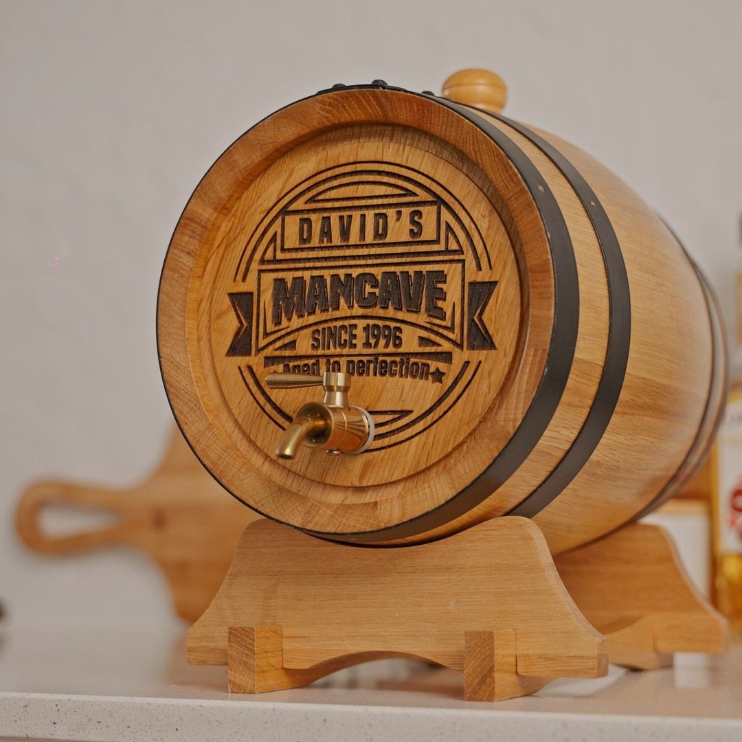 Personalized wooden whiskey barrel on a stand with engraved Mancave text and spigot.