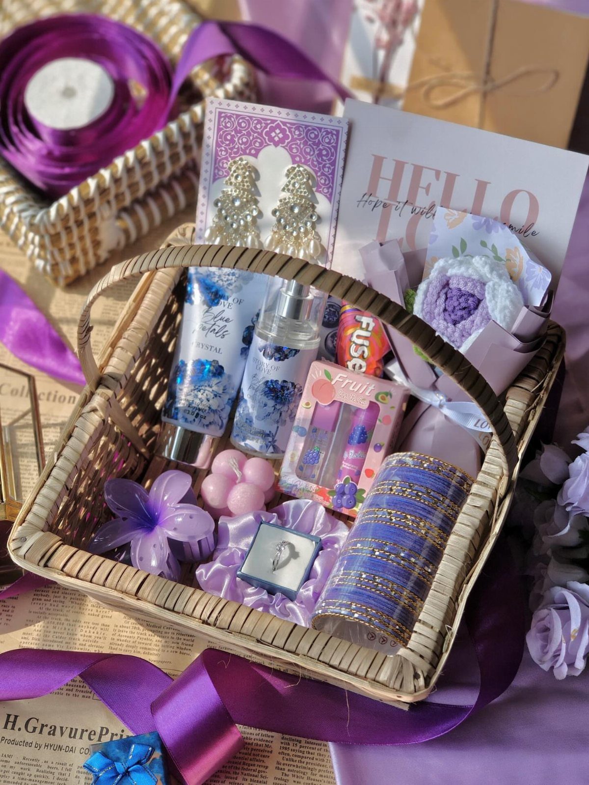 Wicker gift basket filled with purple skincare, jewelry, and a greeting card.