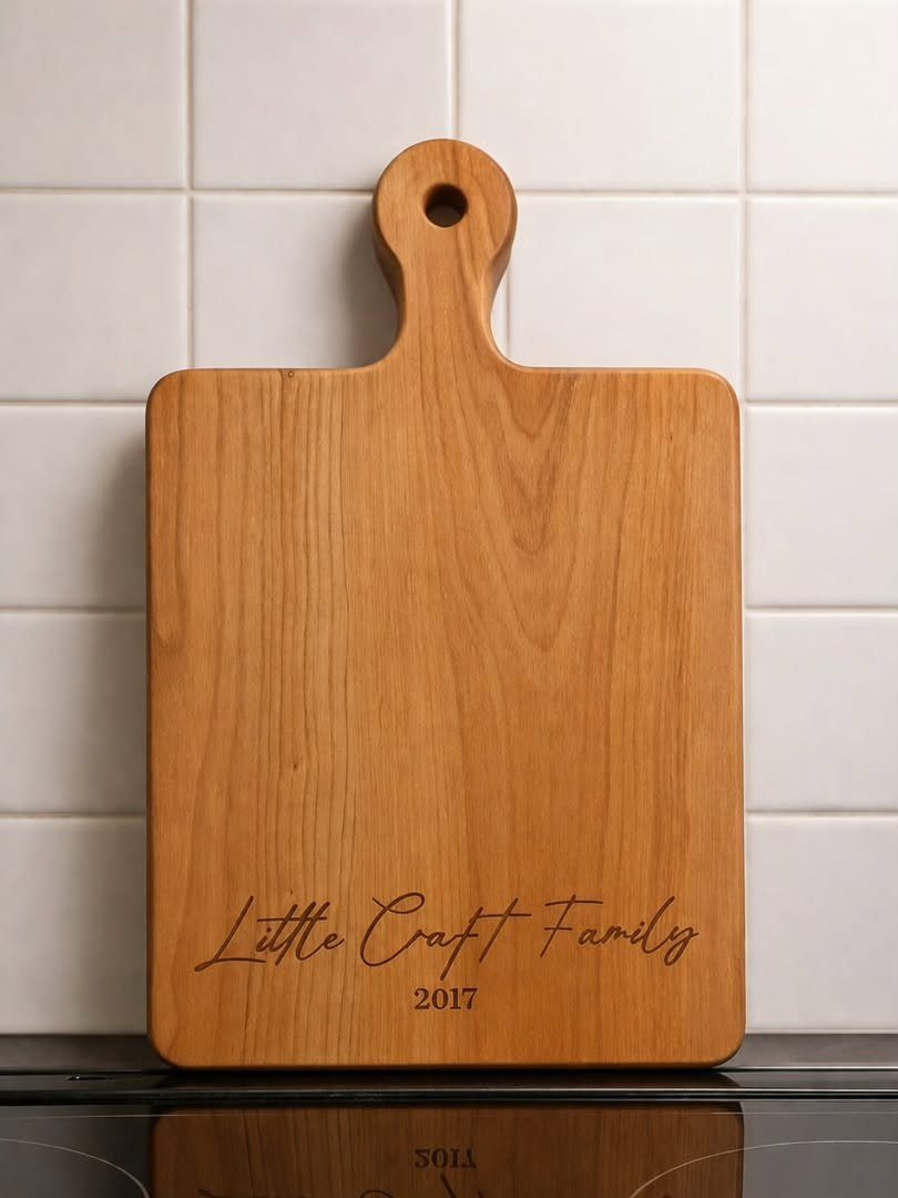 Wooden chopping board with engraved family name and date against white tiles