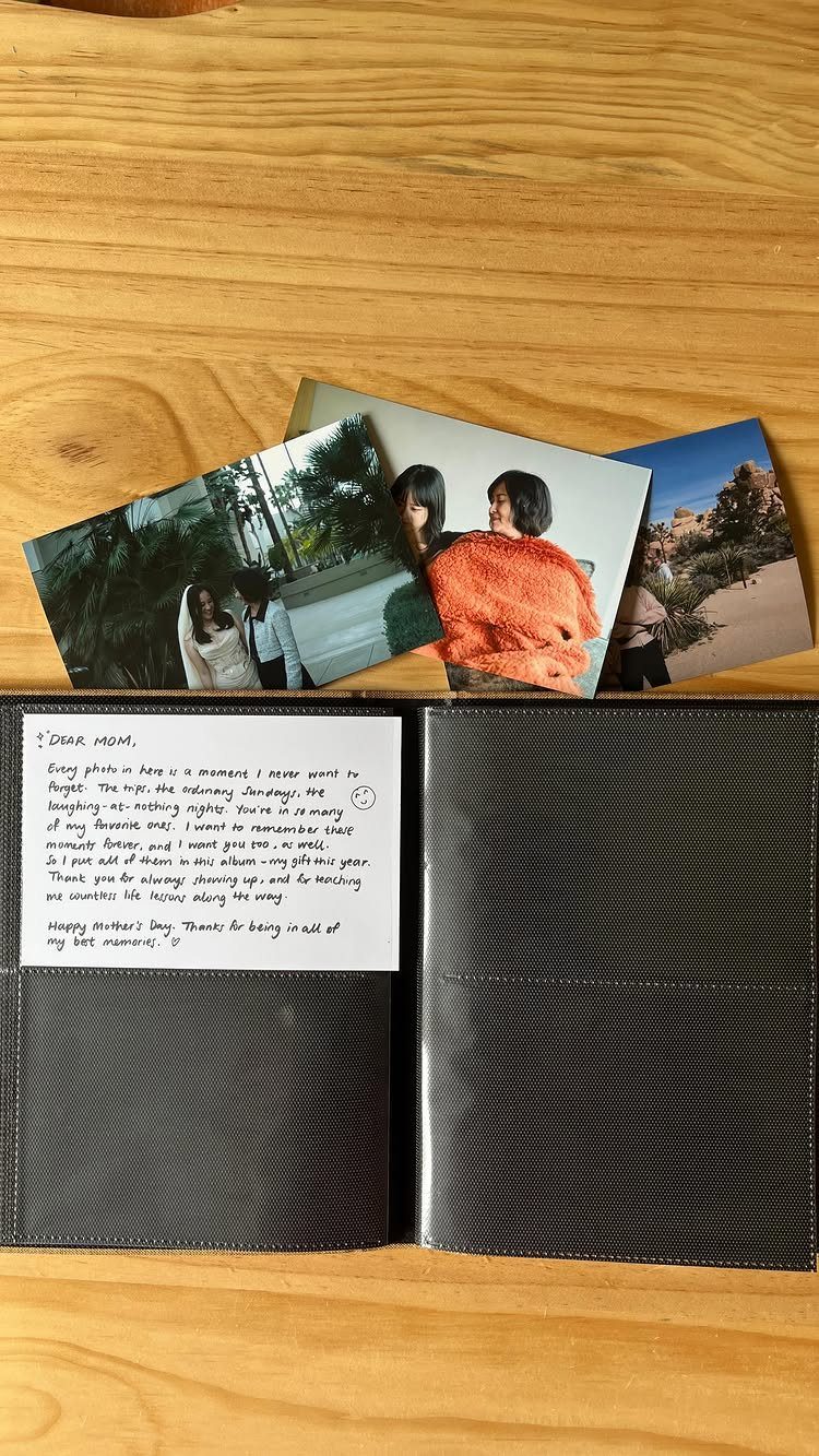 Open black leather photo album with a handwritten note and scattered photographs.
